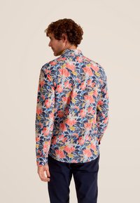 Langarmshirt met een levendig bloemenpatroon van roze en gele bloemen op een blauwe achtergrond, afgewerkt met een strakke kraag.