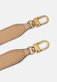 Cinturino in pelle tan con finitura testurizzata, dotato di clip in metallo dorato e dettagli di cucitura lungo i bordi.