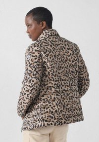 Chaqueta acolchada beige con un estampado de leopardo. Tiene un cuello alto y está acolchada para aislamiento, con un parche de logo en la manga.