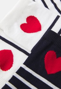 Calze fino al ginocchio con strisce alternate bianche e blu navy, decorate con cuori rossi nelle sezioni bianche e in tessuto blu navy solido nella parte superiore.