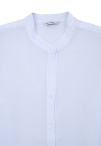 Camicia bianca in lino con colletto alla cinese, chiusura frontale a bottoni e tessuto leggermente testurizzato. L'etichetta riporta "CALLIOPE" con taglia "S."