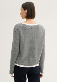 Schwarz-weißer karierten Pullover mit weitem Ausschnitt und langen Ärmeln, ausgestattet mit einem weißen gerippten Saum und Bündchen, von hinten gezeigt.