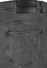 Jeans de mezclilla negros con un único bolsillo trasero, tela texturizada y una etiqueta de marca de cuero en la cinturilla, con costuras de contraste.