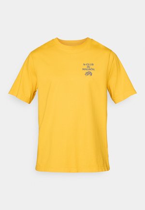 Gelbes Baumwoll-T-Shirt mit kurzen Ärmeln und Rundhalsausschnitt. Fronttext in Blau lautet "le CLUB du MALBÔN". Einfaches, unauffälliges Design.