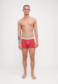 Boxeri scurți roșii din bumbac, cu un brâu elastic alb, având logo-ul "POLO RALPH LAUREN". Design ajustat și textură netedă.