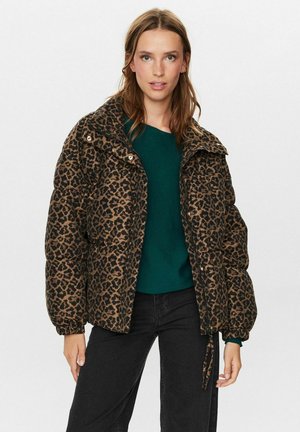 Dierenprint pufferjack met een bruin en zwarte luipaardpatroon, een ritssluiting aan de voorkant en elastische manchetten, gedragen over een groene top en zwarte broek.
