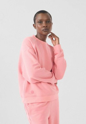 Roze sweatshirt van zacht materiaal met een ronde halslijn en geribde mouwen. Heeft een klein logo-detail aan de onderkant.
