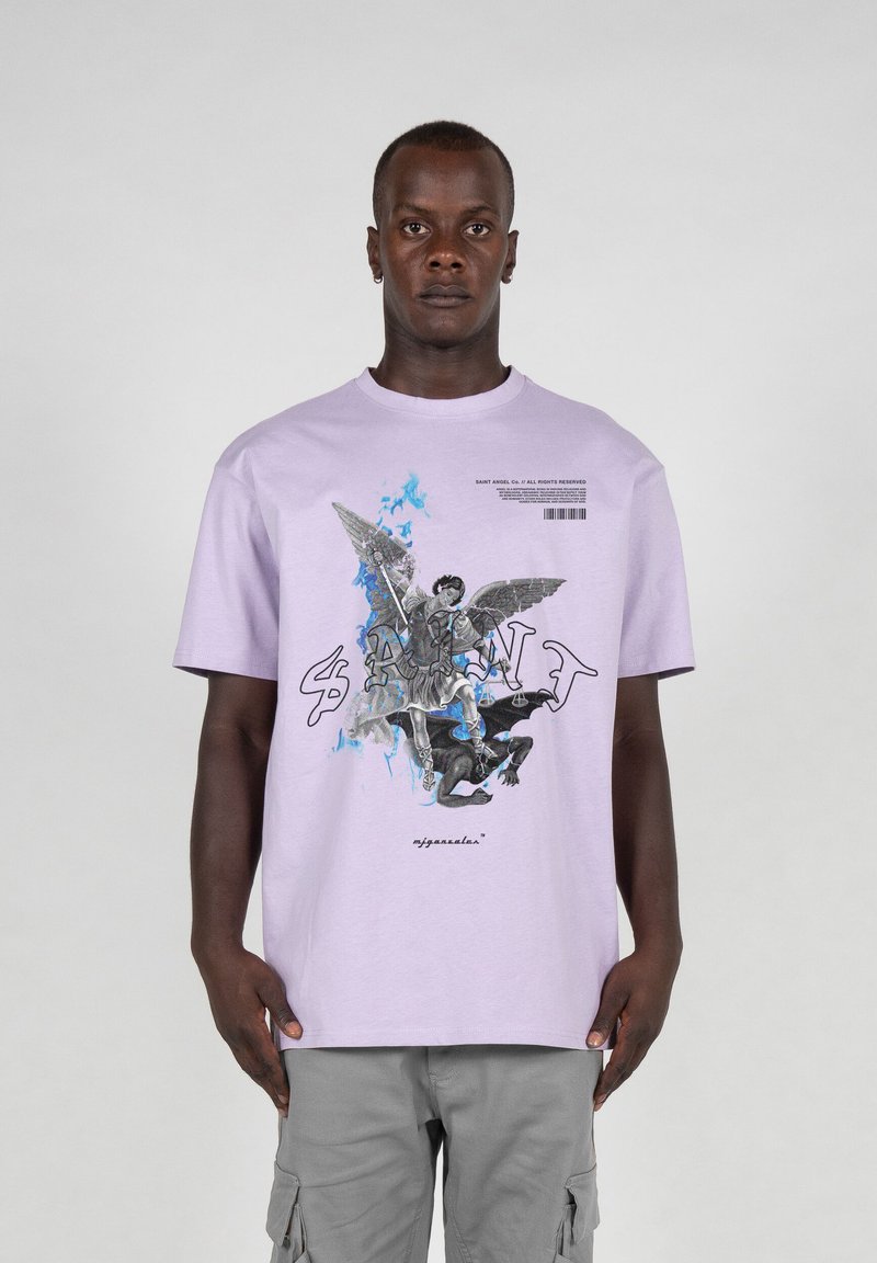 Lilla kortærmet t-shirt med et grafisk print, der viser en figur med vinger og en dæmonisk enhed, med blå accenter og fed tekst.
