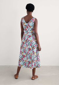 Robe sans manches à motifs floraux, avec un dos en V, de longueur genou, présentant des motifs multicolores sur un fond bleu clair, et une forme évasée. 