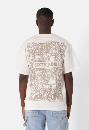 Witte katoenen t-shirt met een grote beige graphic op de achterkant, die sierlijke patronen en de tekst "SIXTH JUNE" toont. Korte mouwen en een relaxed fit.