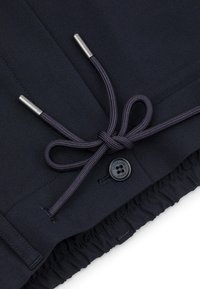 Granatowe szorty z suwakiem i metalowymi końcówkami, z guzikiem z wygrawerowanym logo oraz elastycznym pasem.