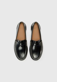 Schwarze Leder-Slipper mit gesticktem Design, glatter Oberfläche und runder Zehenpartie. Mit einem dekorativen Riemen über der Vorderseite.