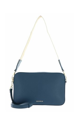 Sac bandoulière rectangulaire en cuir bleu marine avec ferrures dorées, sangle d'épaule beige réglable et nom de la marque "Coccinelle" en lettres dorées.