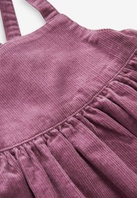 Vestido de pana morado con tirantes ajustables, textura fruncida en la cintura y un acabado suave y acanalado.