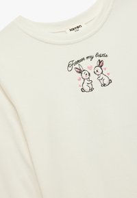 Hvid bomulds sweatshirts med et broderet design af to tegneseriekaniner og teksten "For altid min bedste ven" ovenfor. Blød tekstur, rund halsudskæring.