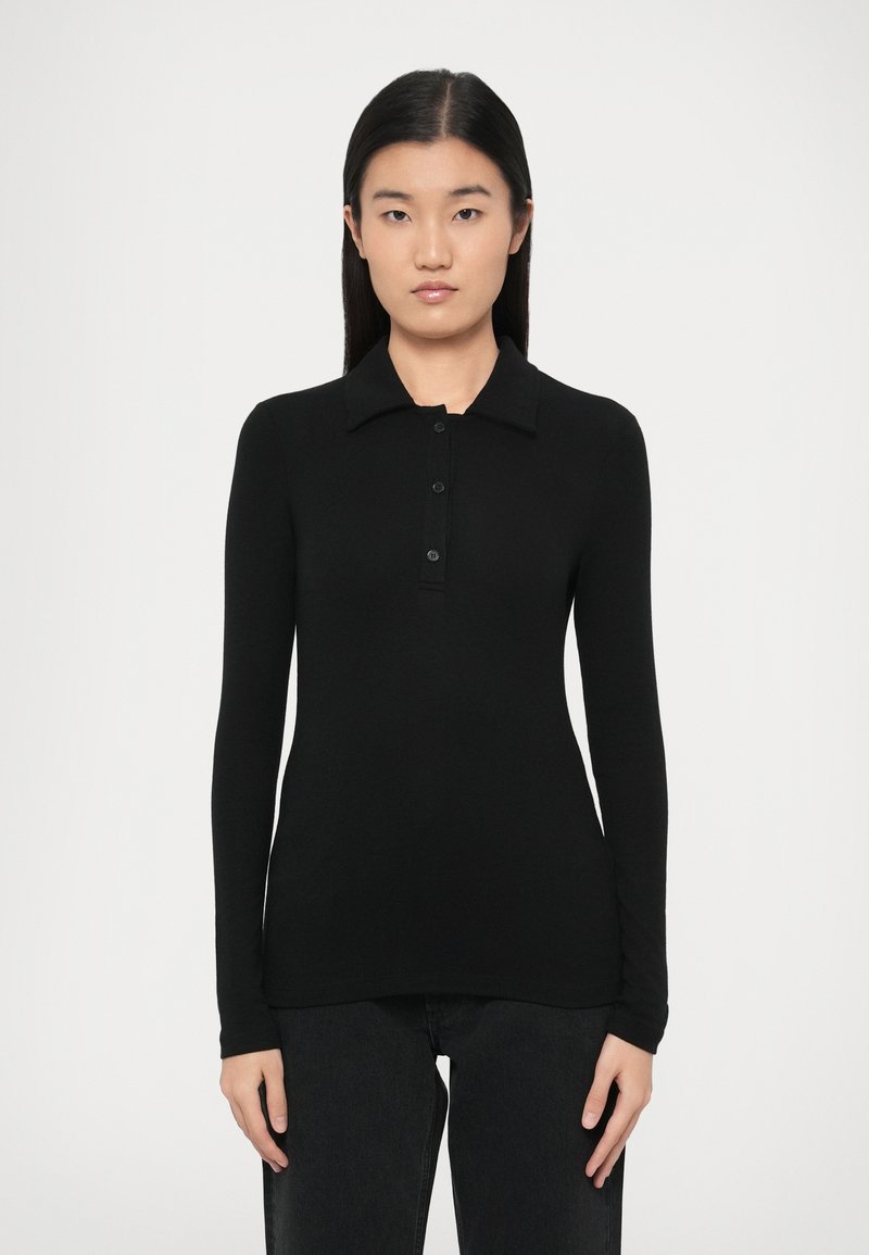 Μαύρο πόλο με μακριά μανίκια, γιακά και μπροστινό άνοιγμα με κουμπιά. Κατασκευασμένο από λείο ύφασμα, με εφαρμοστή σχεδίαση.