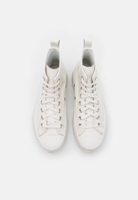 Paire de baskets montantes blanches avec lacets, œillets métalliques et languettes, vues de dessus sur un fond blanc uni.