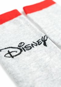 Calze grigie con un risvolto rosso, caratterizzate da un logo "Disney" ricamato in nero. Realizzate in un tessuto morbido con una superficie liscia.