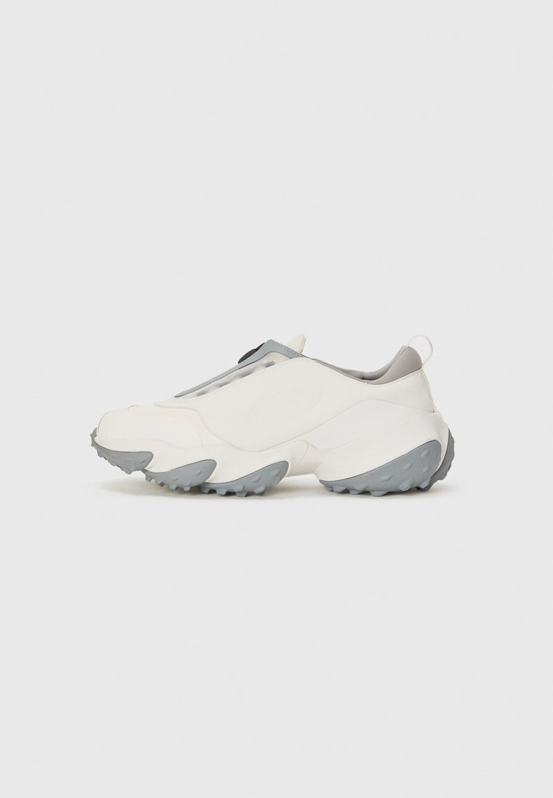 White athletic shoes with gray accents, a textured rubber sole, and a sleek design. Features a pull tab on the heel and slip-on construction.