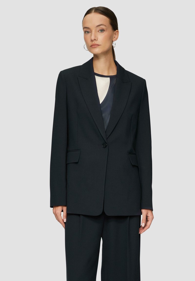 Black tailored blazer with a single button closure, notch lapels, two front pockets, and a smooth texture, paired with matching trousers.
