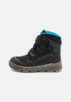 Schwarze wasserdichte Stiefel mit blauen Akzenten, ausgestattet mit zwei verstellbaren Klettverschlüssen, einer strukturierten Gummisohle und gesteppten Seiten zur Isolierung.
