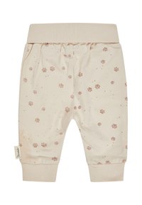 Cremefarbene Kinderhose mit kleinen braunen Pfotenabdrücken, elastischem Bund und gerippten Bündchen für eine bequeme Passform.