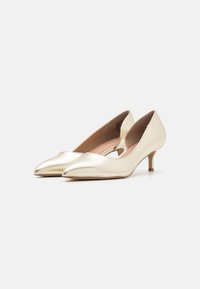 Pumps in pelle oro a punta con tacco basso e dettagli ritagliati sui lati. Texture liscia e leggero luccichio. Forma classica.