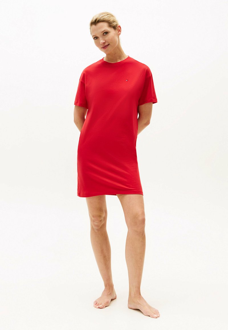 Rotes T-Shirt-Kleid mit kurzen Ärmeln aus weichem Stoff. Es verfügt über ein schlichtes Design und ein Logodetail auf der Brust.