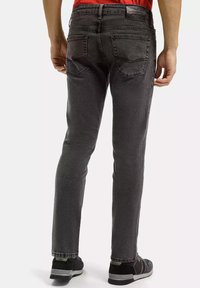 Męskie szare dżinsy o slim fit, z tylnymi kieszeniami i gładką teksturą, połączone z czarnymi butami.