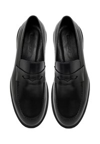 Mocasines de cuero negro con un diseño plano, que presentan una punta redondeada y una banda decorativa a lo largo del empeine. Textura lisa, sin herrajes visibles.