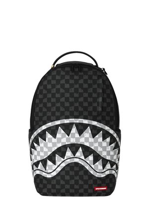Mochila a cuadros negra y gris con un gran gráfico blanco de una boca de tiburón y dientes afilados en el bolsillo frontal.