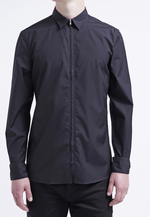 Chemise noire à manches longues avec une fermeture éclair à l'avant, un col pointu et des poignets à boutons. Tissu lisse et léger avec une coupe ajustée.