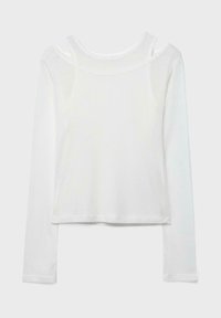 Chemise blanche à manches longues côtelées avec un détail de col superposé, comprenant une couche de débardeur sous un large col bateau.
