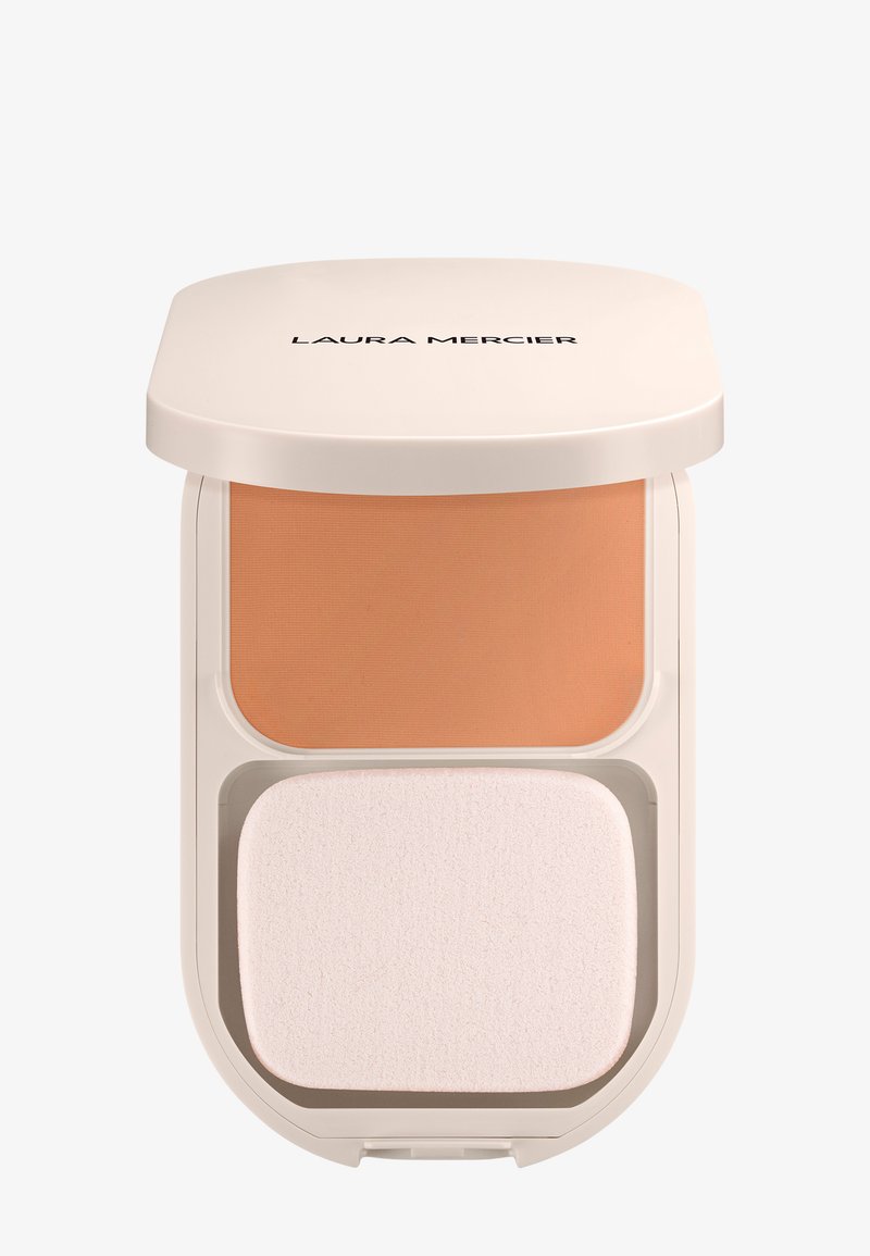 Cipria compatta in beige chiaro e rosa morbido, con una consistenza liscia e una spugna applicatrice bianca in una confezione rettangolare arrotondata.