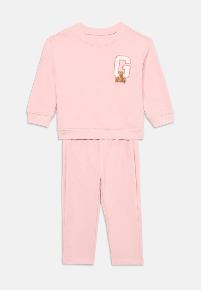 Conjunto de pijama em algodão rosa, com sweatshirt de gola redonda e mangas longas, e um logotipo de urso de pelúcia, combinado com calças de cintura elástica.