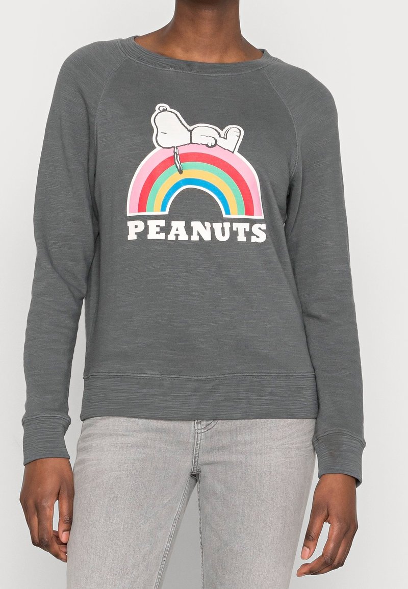 Sudadera gris de manga larga, que presenta un gráfico de Snoopy sobre un arcoíris, texto negro "PEANUTS" y detalles de canalé en el dobladillo y los puños.
