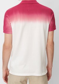 Polo à manches courtes avec un design dégradé passant du rose au blanc, fabriqué à partir d'un tissu texturé avec un col et un ourlet côtelés.