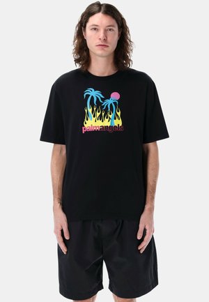 Maglietta nera in cotone con un design grafico di palme blu, un sole rosa e fiamme gialle, con il testo "palmangels" in rosa.