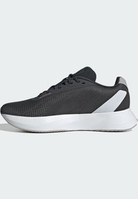 Černá sportovní bota s texturovaným síťovaným svrškem, bílou mezipodešví a kontrastními šedými akcenty. Lehké, aerodynamické provedení pro pohodlí.