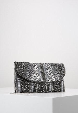 Clutch met zilveren en zwarte kralen- en paillettenversieringen in geometrische patronen, rustend op een witte ondergrond met een zilveren kettingriem.