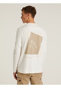 Langärmliges weißes T-Shirt mit einem grafischen Design auf dem Rücken, in beige- und brauntönen, rechteckiger Form und lockerer Passform.