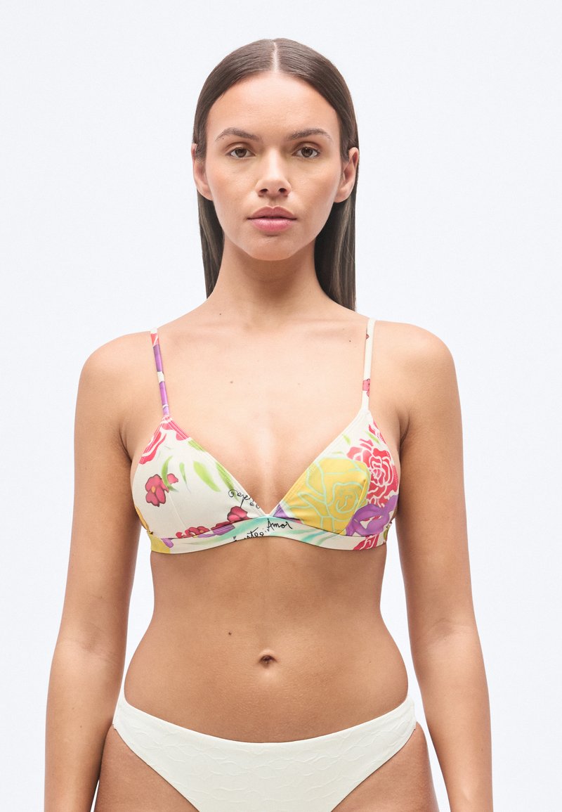 Τοπ μπικίνι με λουλουδάτο μοτίβο σε εκρού απόχρωση, με τριγωνικό σχήμα, λεπτές τιράντες και διακριτικό λογότυπο. Οι λευκές υφασμάτινες βερμούδες συμπληρώνουν το σχέδιο.