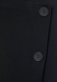 Schwarzer Stoff mit glatter Textur und einem auffälligen schwarzen Knopfdetail auf der linken Seite, das ein klares, einfaches Design zeigt.