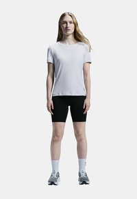 Ljusgrå, kortärmad träningsskjorta som matchas med svarta shorts, vita strumpor och grå sneakers. Slät tyg, figurnära design.