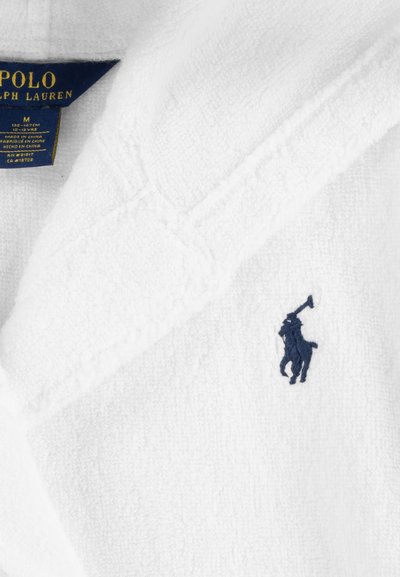 Balta frotinė chalatą su šalikine apykakle ir tamsiai mėlynu siuvinėtu logotipu. Yra etiketė su prekės ženklu ir dydžio informacija.