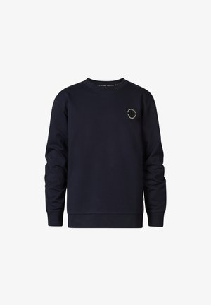Granatowy sweatshirt z długimi rękawami, okrągłym dekoltem i okrągłą naszywką z logo na piersi, w zestawie z jasnoszarymi dopasowanymi dżinsami i czarnymi trampkami.