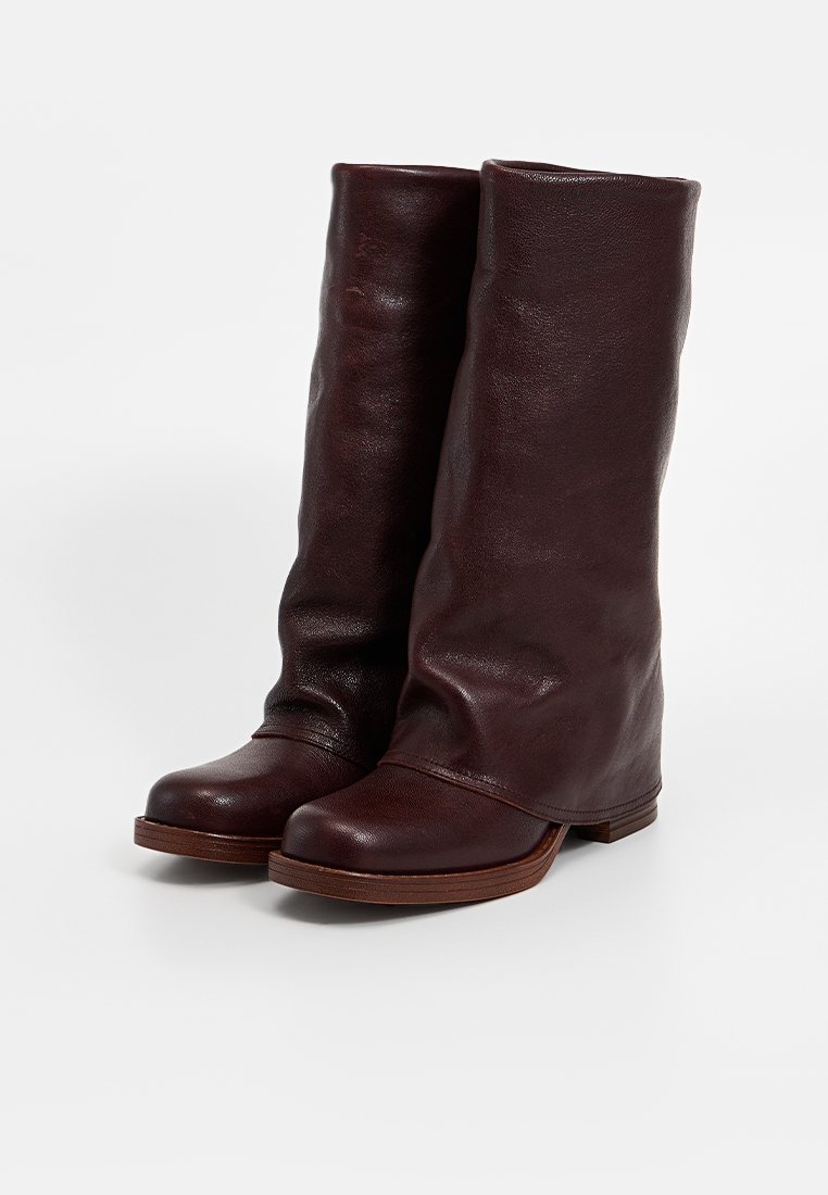 Bottes en cuir marron jusqu'au genou avec un design doux et décontracté, bout arrondi et talon en bois robuste. Fini poli avec une texture lisse.