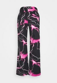 Pantalones negros de pierna ancha con patrones de rayos en rosa brillante y blanco, vistos desde atrás sobre un fondo liso.