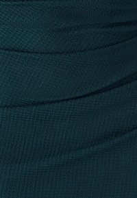 Teal textured fabric with a slightly ribbed pattern, featuring horizontal draping and subtle sheen. Suitable for garment construction.