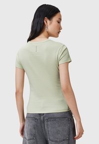 T-shirt verde chiaro a maniche corte con una forma aderente e scollo rotondo, con un piccolo'etichetta sul retro vicino al collo.